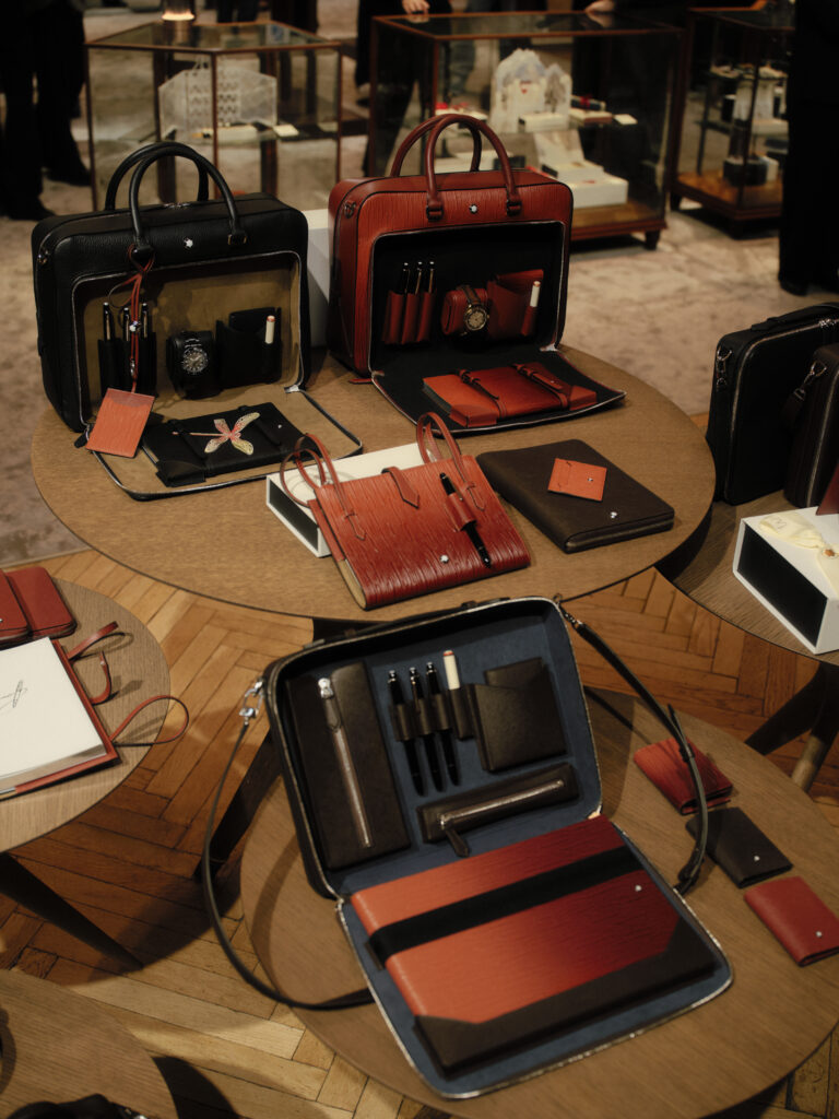 maletines de Montblanc en color negro naranja y azul marino, con los cierres frontales abiertos y con accesorios