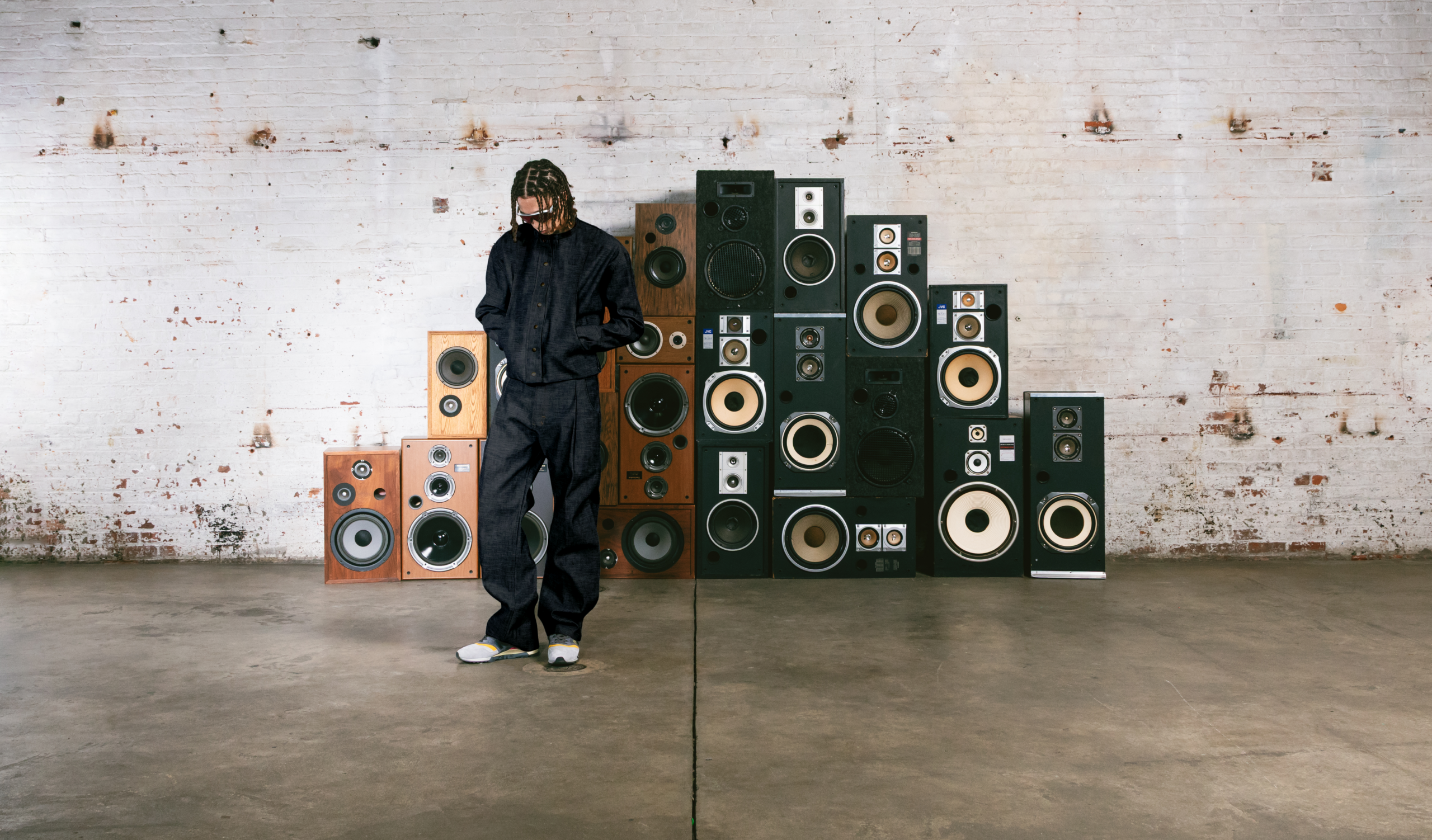 Fondo de pared blanca con bocinas negras y cafe, al frente modelo