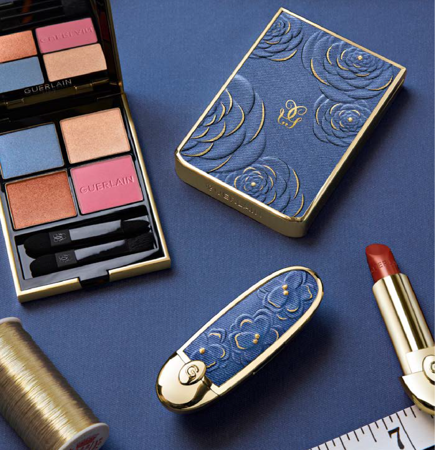 Fondo azul medio con productos de la colección primavera 2026 de Guerlain como sombra y labiales mostrando su empaque azul medio