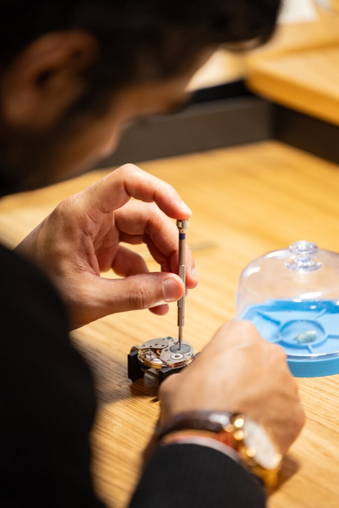 Persona en Watches and Wonders arreglando un reloj con un instrumento especial para la reparación de relojes 