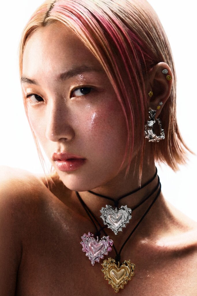 Modelo con collares de corazón rosa, plateado y dorado con lazos  de edición de "Jardin del Placer" 