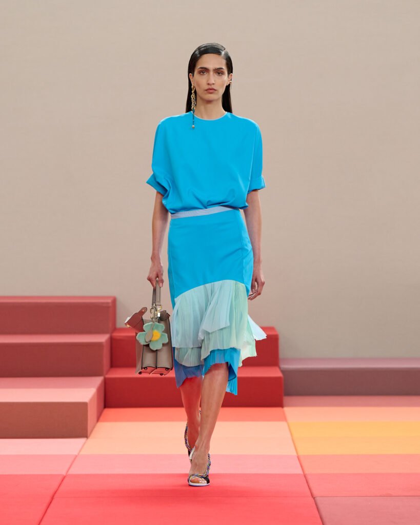 modelo recorriendo la pasarela. Look de FENDI SS26 Runway Look. Falda y blusa en combinación con el bolso y charm